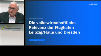 Auf dem Bild ist Sachsen-Anhalts Finanzminister Michael Richter zu sehen sowie eine Powerpoint-Seite mit Informationen zur volkswirtschaftlichen Relevanz der Flughäfen Leipzig-Halle und Dresden..